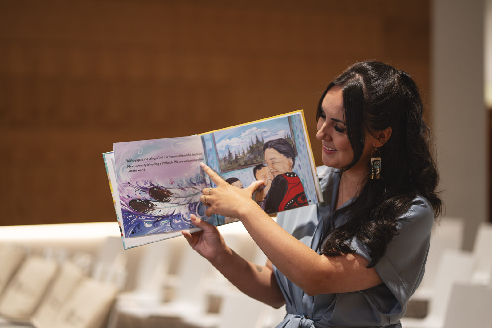 Indigenous author and teacher, Samantha Beynon, holding her book Celebrating Potlatches, sharing Indigenous stories that celebrate culture and learning.
